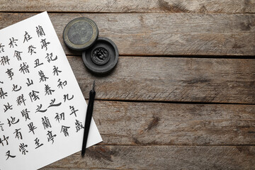 Tools for calligraphy and paper with Asian hieroglyphs on wooden background - obrazy, fototapety, plakaty