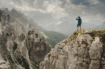 Man in Blue jacket standing on a Dolomite mountain in Italian alps with mountains in background