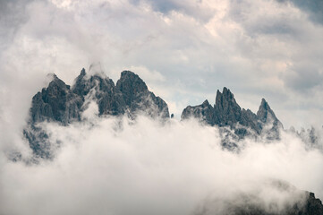 Rocky dolomite mountains covered with clouds and mist in Tre Cime area, Italy