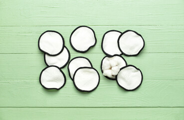 Reusable cotton pads and flower on color wooden background