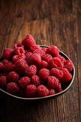 Raspberry in a ceramic bowl over wooden rustic background