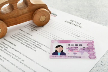 Fototapeta na wymiar Rental agreement, driver license and wooden car, closeup
