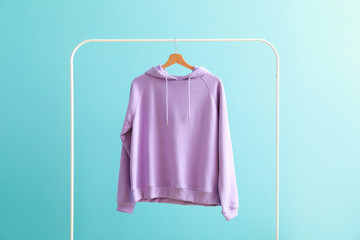 Rack with hoodie on color background
