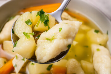 Spoon with tasty dumpling soup, closeup