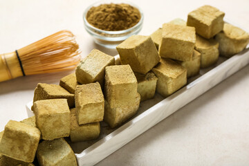 Plate with tasty hojicha marshmallows, powder and chasen on light background, closeup