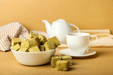 Bowl with tasty hojicha marshmallows and cup of tea on color background