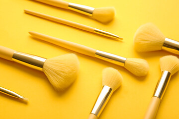 Set of stylish makeup brushes on yellow background