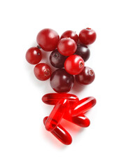 Cranberry pills and heap of berries on white background