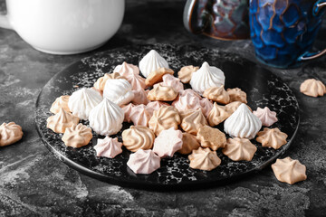 Board with tasty meringues on dark background