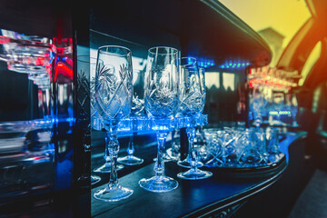 Glass glasses in neon lighting inside the luxury car limousine - obrazy, fototapety, plakaty