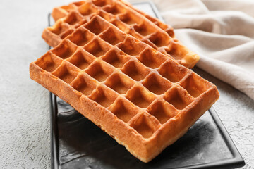 Board with yummy Belgian waffles on light background, closeup