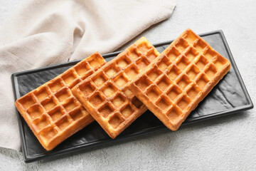 Board with yummy Belgian waffles on light background