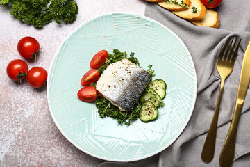 Plate of delicious sea bass fish with vegetables on light background
