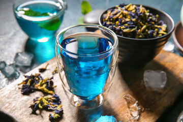 Glass of organic blue tea and dried flowers on table, closeup