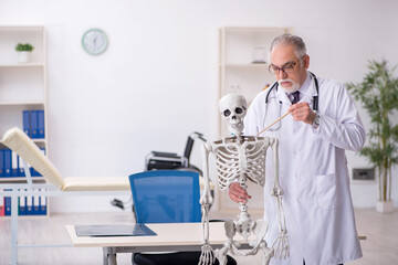 Old male doctor demonstrating human skeleton