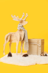 Wooden reindeer with scarf, Christmas gift and fluffy carpet on yellow background