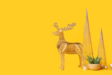 Wooden reindeer with Christmas decor on yellow background