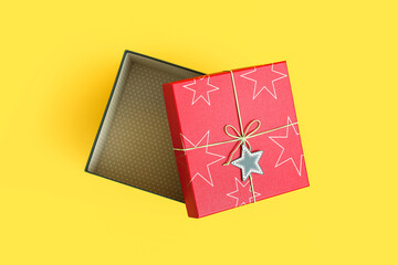 Opened red Christmas gift box with card on color background