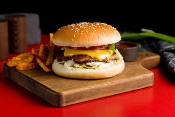 Burger with chicken cutlet on the board on red wooden table