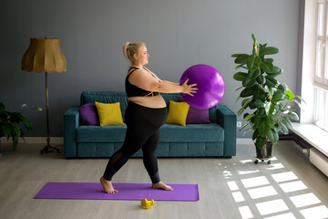 A fat, obese pregnant lady is doing Pilates at home, lifting a fit ball above herself. Home...