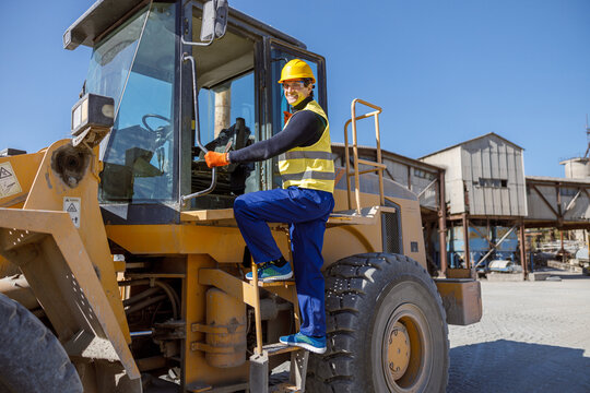 Joyful Man Factory Worker Looking At Camera And Smiling While Standing On Steps Of Industrial Truck