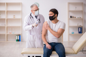 Young male patient visiting old doctor in vaccination concept
