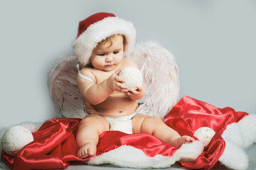 Baby Christmas. Cute funny angel infant with wings in a Santa hat.