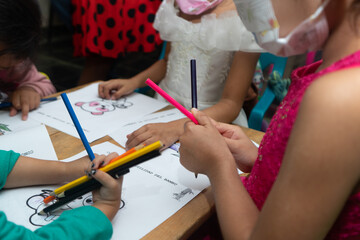 Fototapeta na wymiar Hispanic kids drawing indoors using mask for coronavirus pandemic. Horizontal picture with copy space.