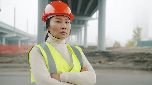 Portrait of female construction engineer Asian lady standing in building area with arms crossed and looking at camera feeling confident at work