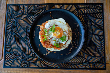 tasty open faced arepa with egg, cheese, tomato, and onion