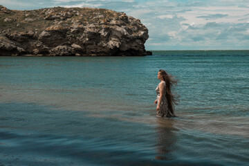 girl with long hair posing in water. treavel by the sea
