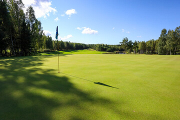 Fototapeta premium Flag shadow on the golf course with green grass. High quality photo