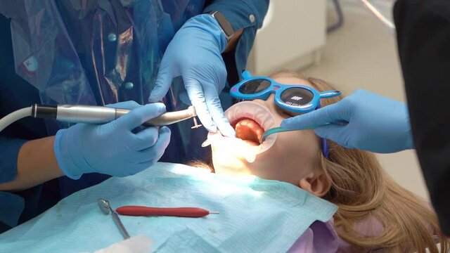 kid girl with oral dilator at dentist's appointment. polishing of teeth