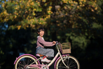 秋の公園で自転車を乗って遊んでいる可愛い子供