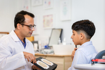 Fototapeta premium Boy doing eye test checking examination with optometrist in optical shop, Indian-thai boy in optics store