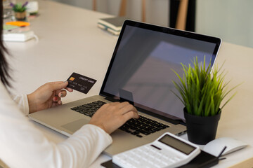 young woman holding credit card and using a laptop computer online shopping, e-commerce, internet banking, spending money, work from home concept and online payment close