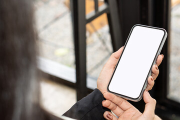 Top view mockup of a woman holding a black cell phone with the blank white screen while sitting at...