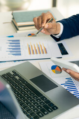 Businessman holding pen pointing to analyze paper, financial graphs, and graphs on the table. and planning investments for business and vertical close-up photo stocks