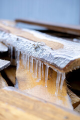 Icicles hang on wooden planks. The first frost in the village.