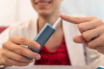 man fills gadget with a cigarette. new smoking technology. Smoker smoking hybrid smokeless...
