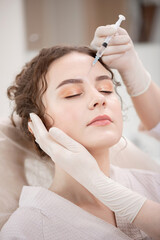 Correction of mimic wrinkles, shape of eyebrows and lips in young curly woman in beauty salon using...