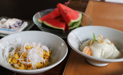 Closeup of sweet corn and coconut in white ceremic dish.