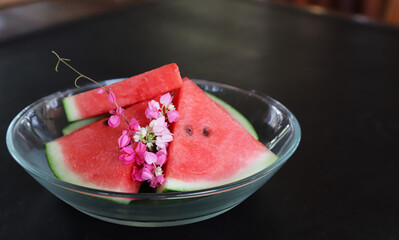 Closeup of fresh watermelon with flower in glass dish.