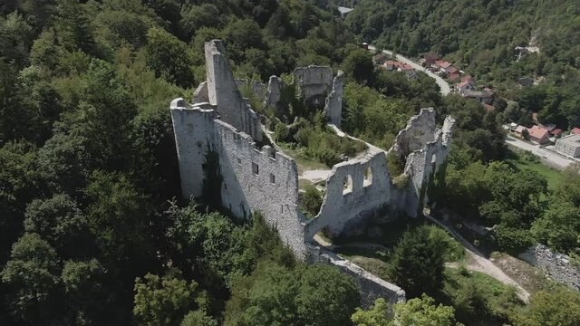 Aerial shot flying away from the historical castle of Samobor revealing green trees and city buildings in the background.