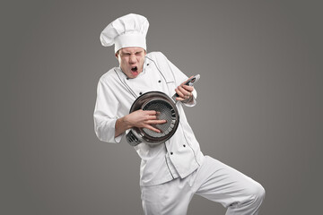 Expressive chef playing on colander like on guitar