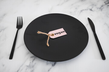 vegan label on top of black dining plate on marble table, healthy nutrition and ethical choices