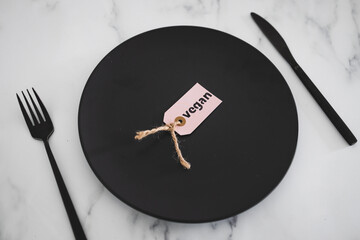 vegan label on top of black dining plate on marble table, healthy nutrition and ethical choices
