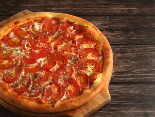 round whole pizza margarita with tomatoes, cheese and spices on a wooden dark background
