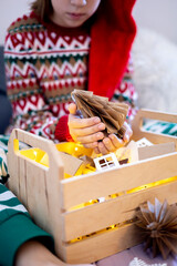 Christmas without waste. Child girl in pajamas sits on the bed and looks at toys for the tree.