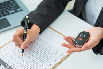 Man signing car insurance document or lease paper. Writing signature on contract or agreement. Buying or selling new or used vehicle. Car keys on table. Warranty or guarantee. Customer or salesman.